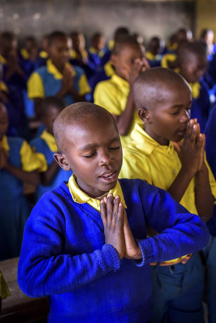 Students pray together at a Bible club meeting in Kenya. The students, many of whom are sponsored, learn Bible verses, sing, hear the Word of God, and plant and care for fruit trees through the ELO Christian discipleship program.
