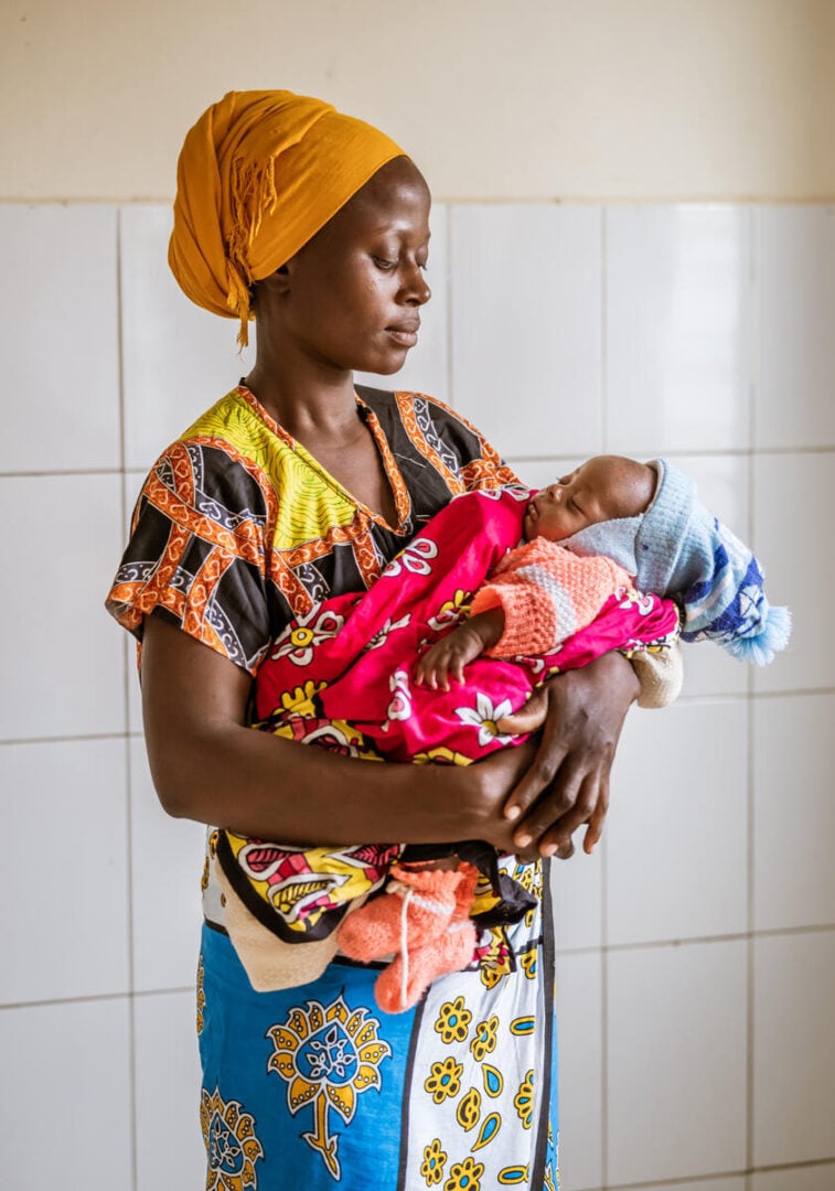 A woman looks down at an infant in her arms.