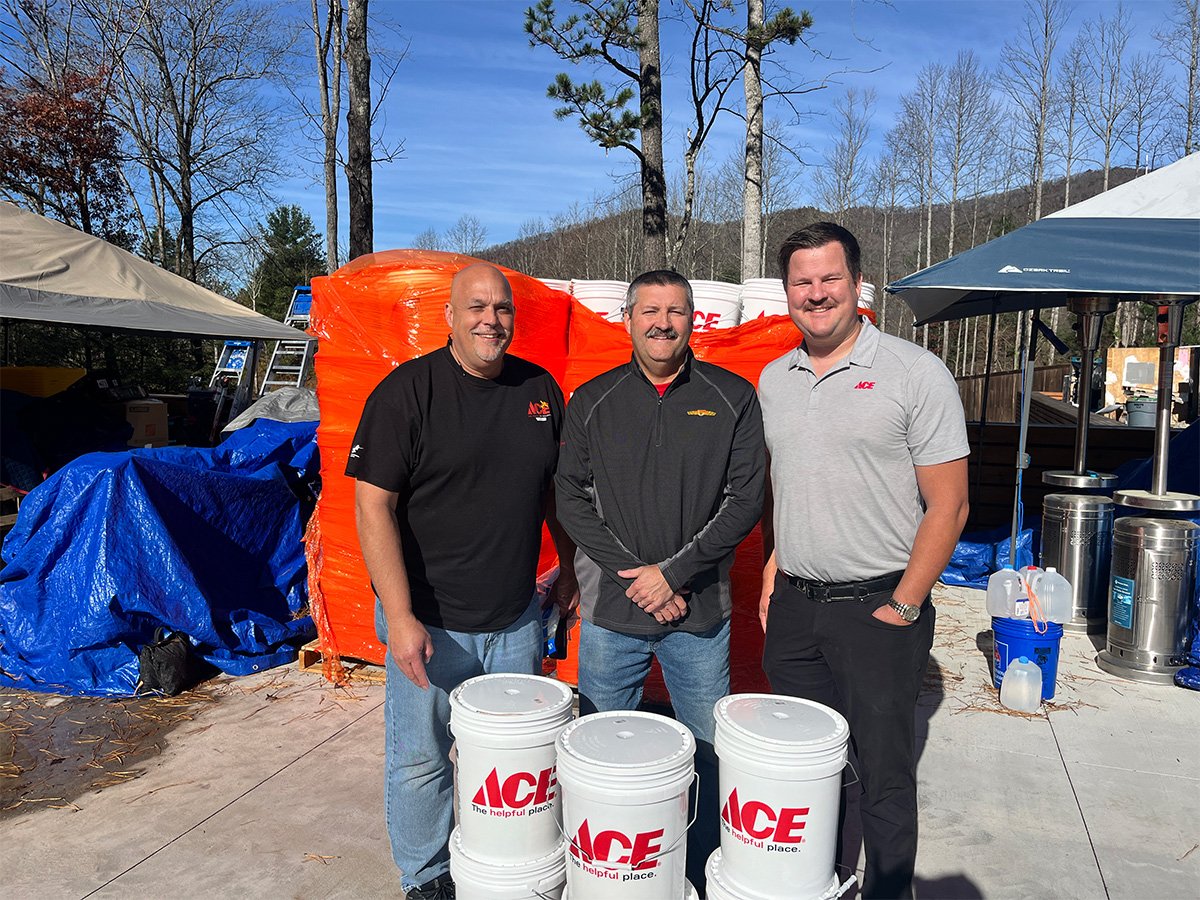 three men standing next to eachother holding Ace hardware buckets