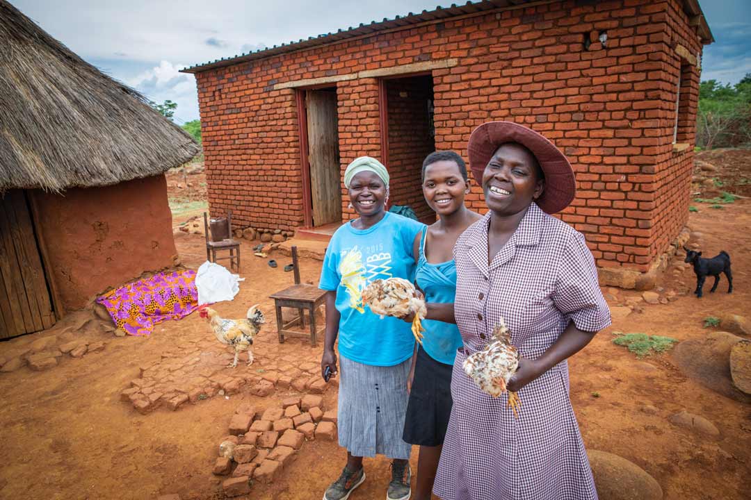 A woman holds chickens that have helped provide her with more money for her household in Zimbabwe.