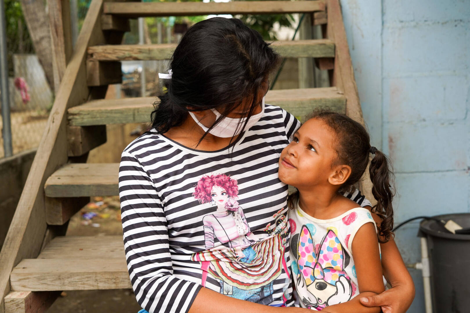 Ana and Briana gaze into each other&rsquo;s eyes as they sit next to each other.