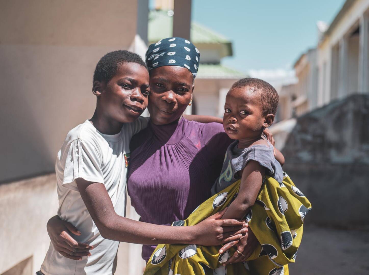 A family in Mozambique stands close to each other as they look at the camera.