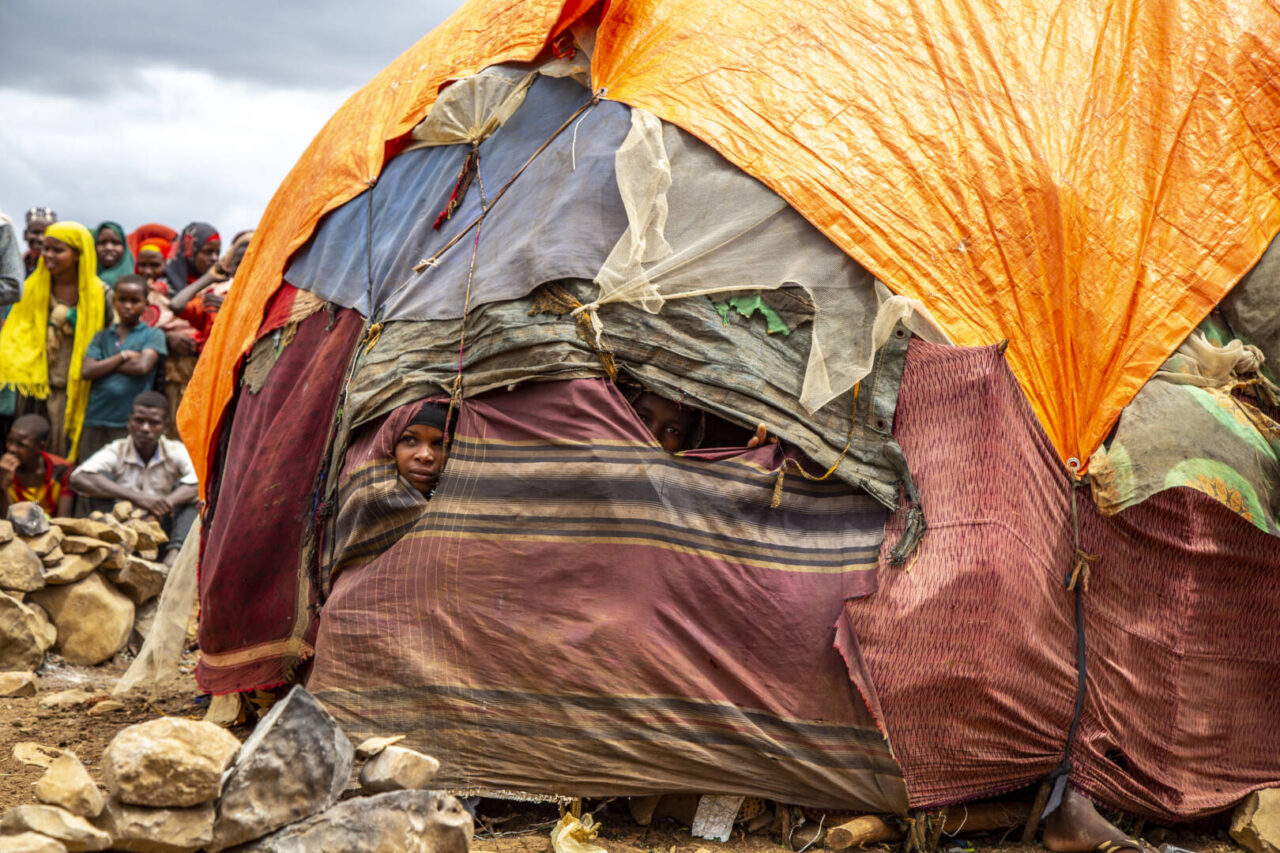 A child peers from behind folds of fabric covering a makeshift shelter in Somalia. 