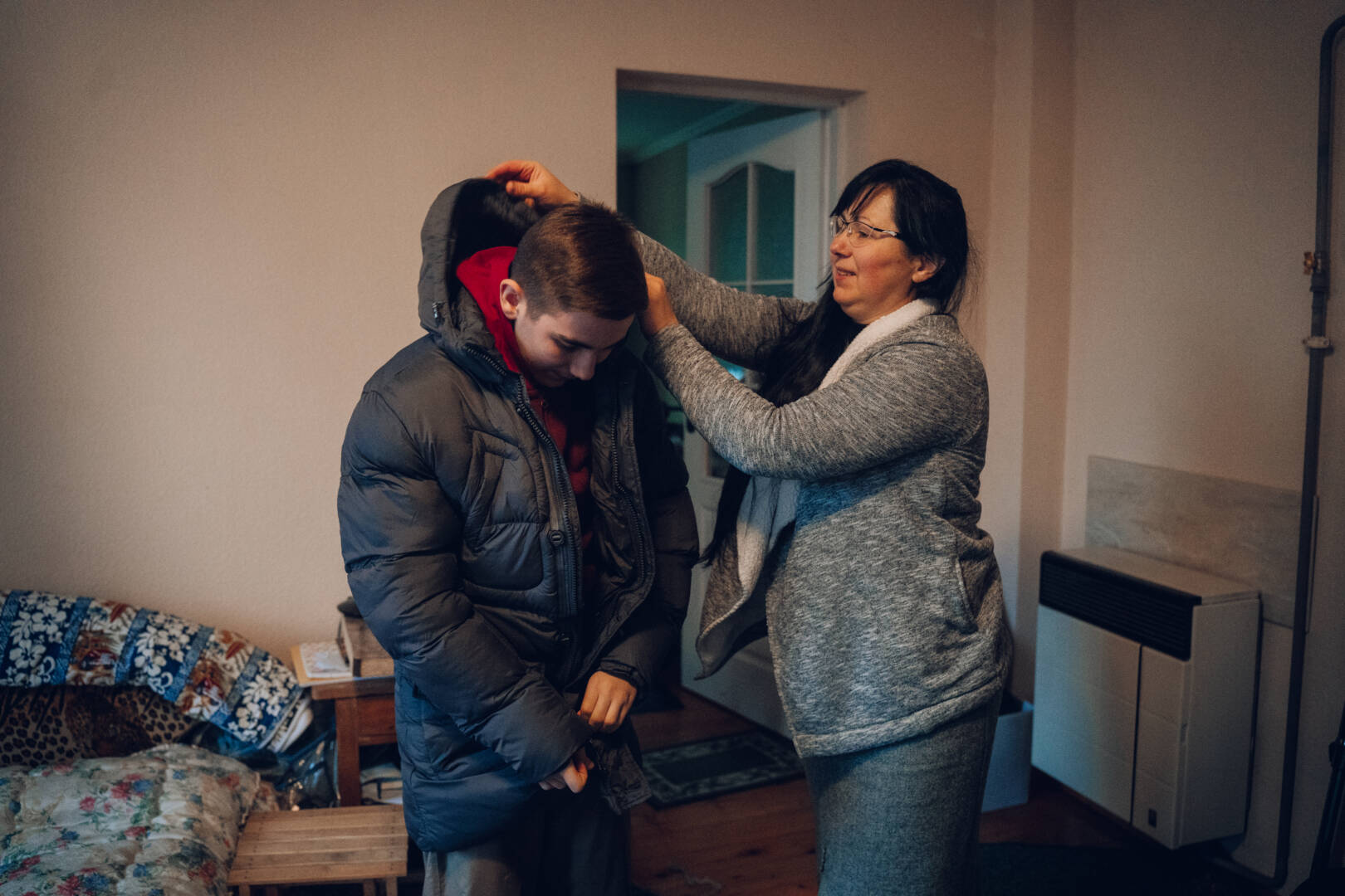 A Ukrainian mother lifts the hood of a new jacket over her son&rsquo;s head as he zips up the winter coat
