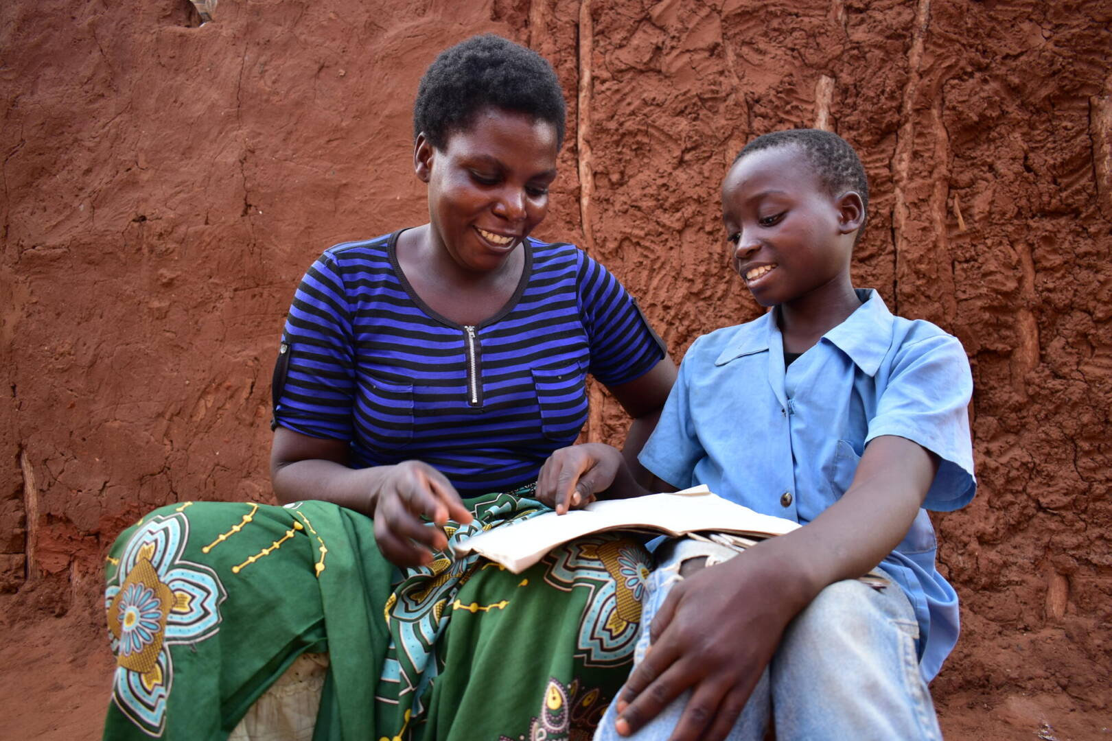 Lonely looks at an open booklet with her stepson, Swangirai.